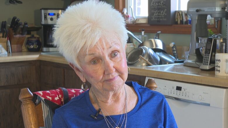 A woman sits in her kitchen.