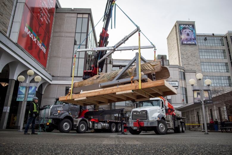 A crane lowers a totem pole belonging to the Nuxalk Nation out of the Royal B.C. Museum in Victoria, British Columbia on Monday February 13, 2023. 