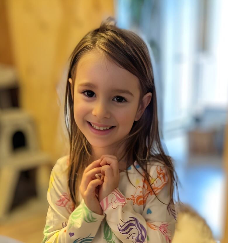 Little girl with long hair smiles at the camera.