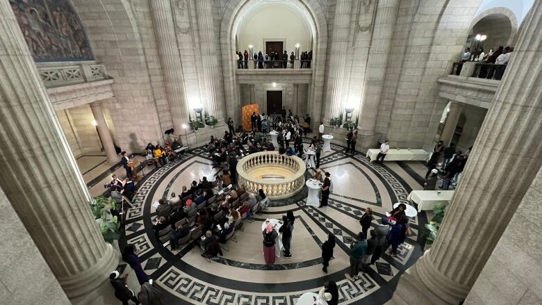 People are pictured in a marble atrium at a bird's eye view.