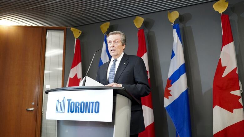 Toronto Mayor John Tory stands at a podium. 