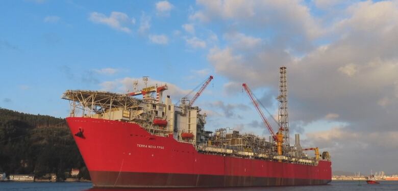 A large red ship with industrial equipment on deck.