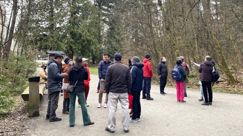 A group of about a dozen Chinese adults stand together in a park.