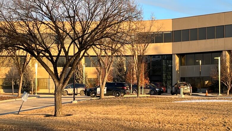 Police and other official vehicles sit parked outside a three-storey industrial office building in Calgary.