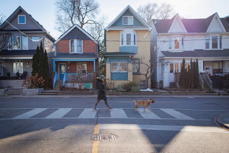 A dog-walker crosses the street in Torontos Pocket neighbourhood on on Dec. 21, 2022. 