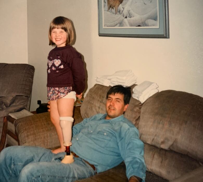 A picture of Allison Lang when she was a small child. She is standing up on a man's knees who is sitting down.