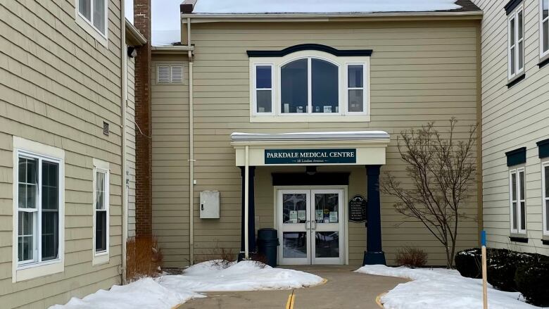 The exterior of a beige office building with a pavement courtyard in front, with snow on the ground. 