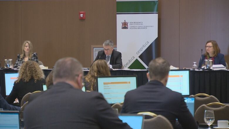 The EUB hearing room, with three people seated at a central table.