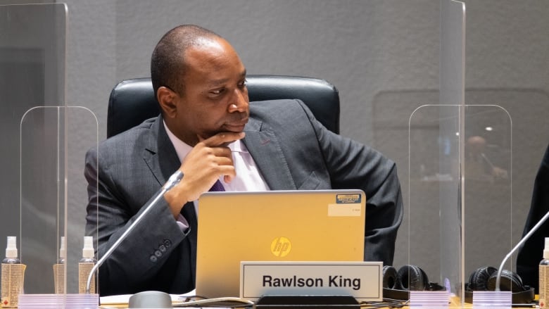 A city councillor listens at his council seat.