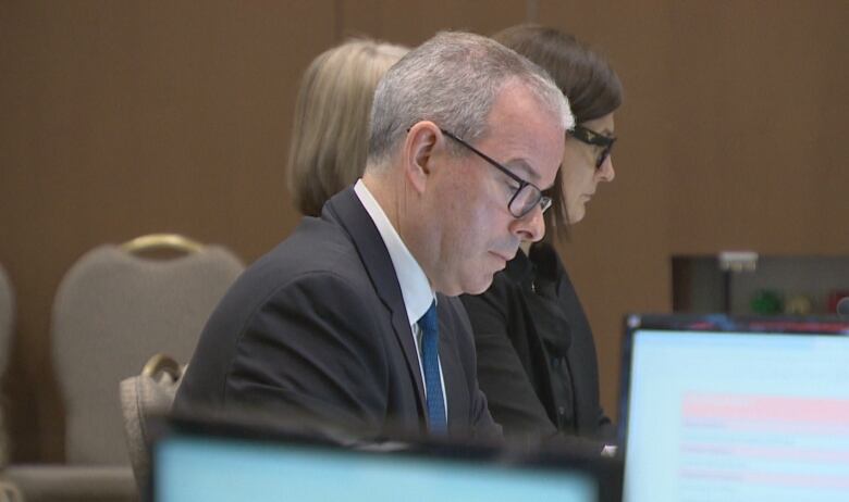 A man's side profile with laptop screens in the foreground