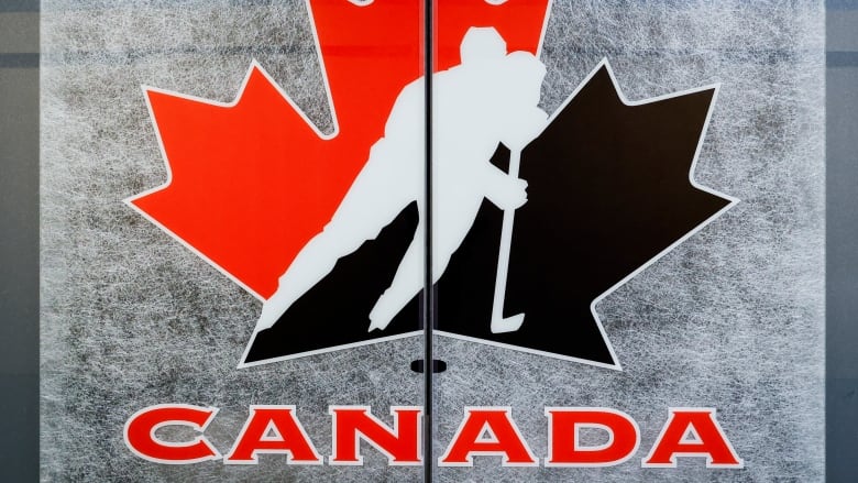 The Hockey Canada logo is seen against a grey backdrop with a line down the middle.