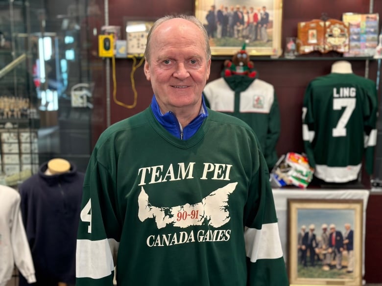 A man wearing a Team PEI hockey jersey stands in front of a display of 1991 memorabilia 