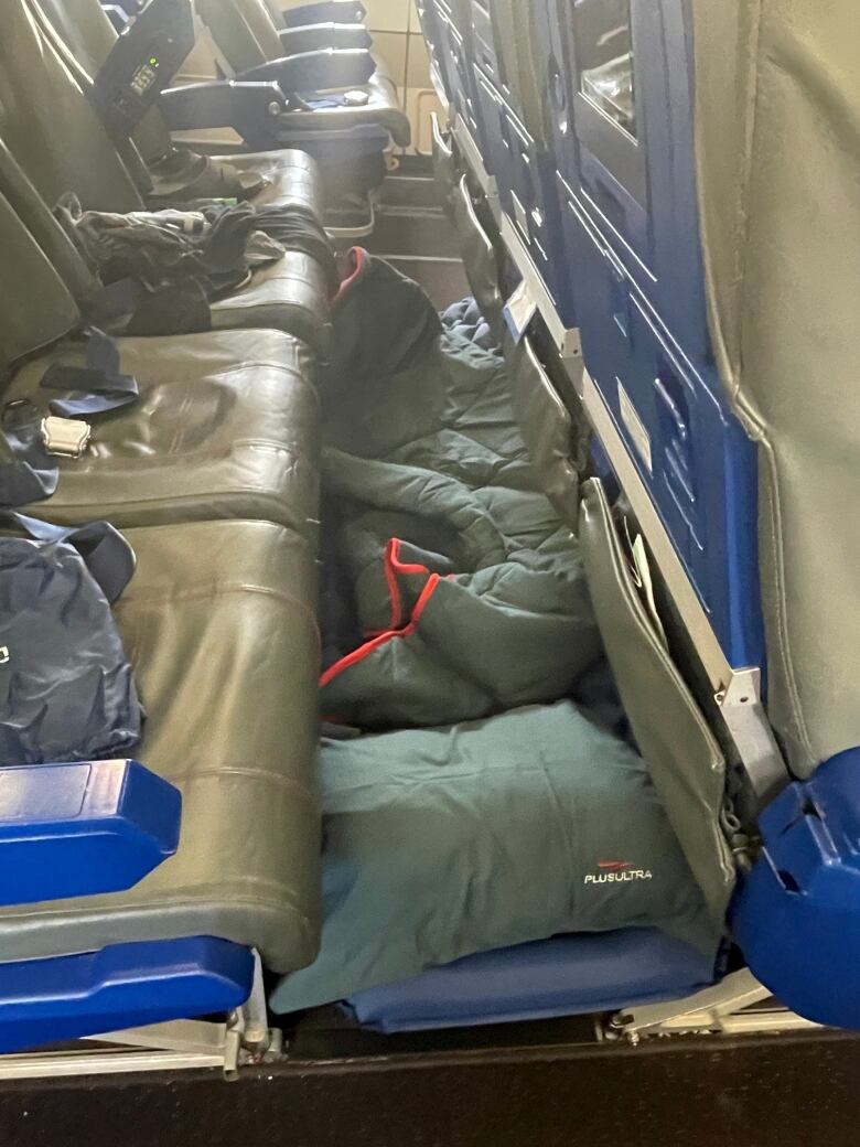 Sleeping bags are rolled out under seats on a plane.