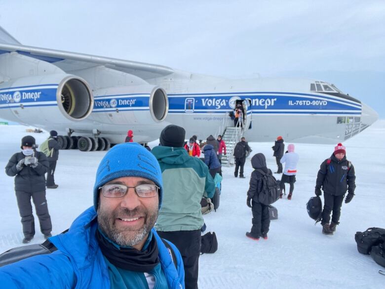 A man poses with an airplane in the background.