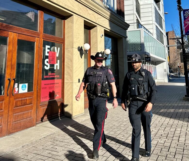 Two officers walk down a street.