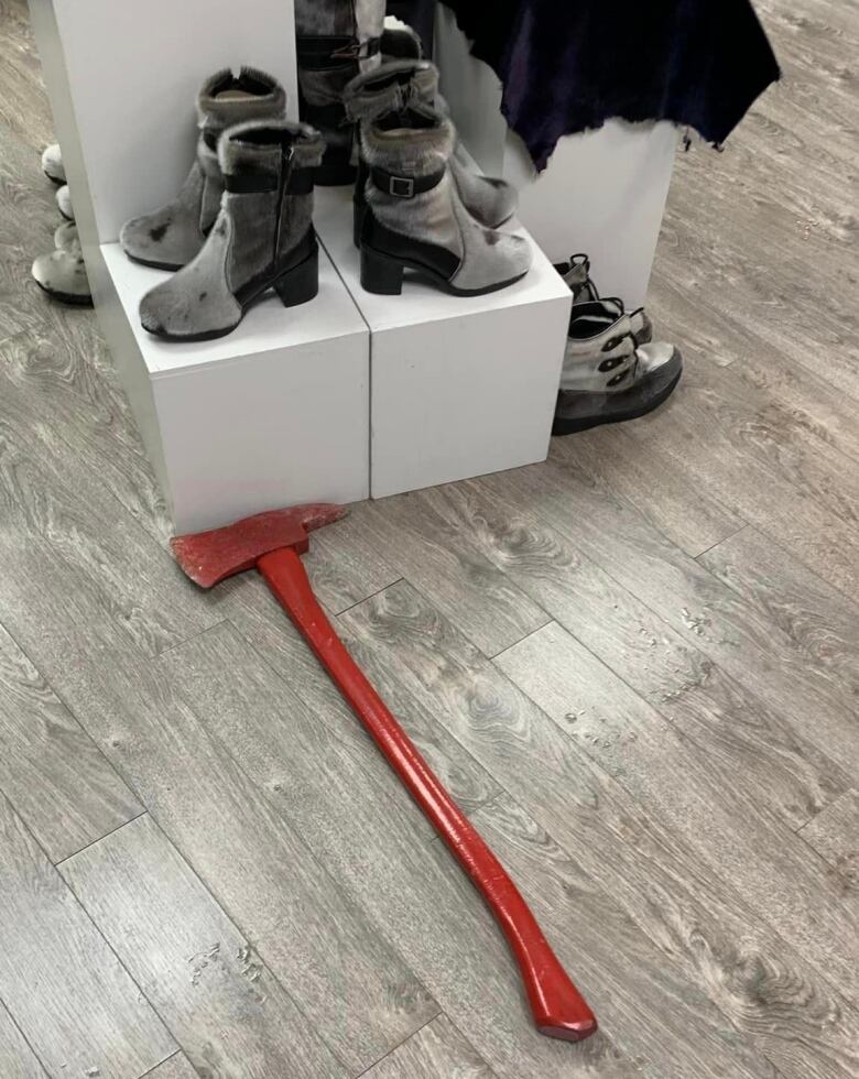 A red axe sits on hardwood flooring in front of a display of sealskin boots.