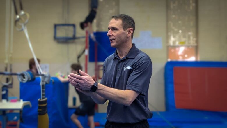 A coach claps his hands encouraging his gymnasts 