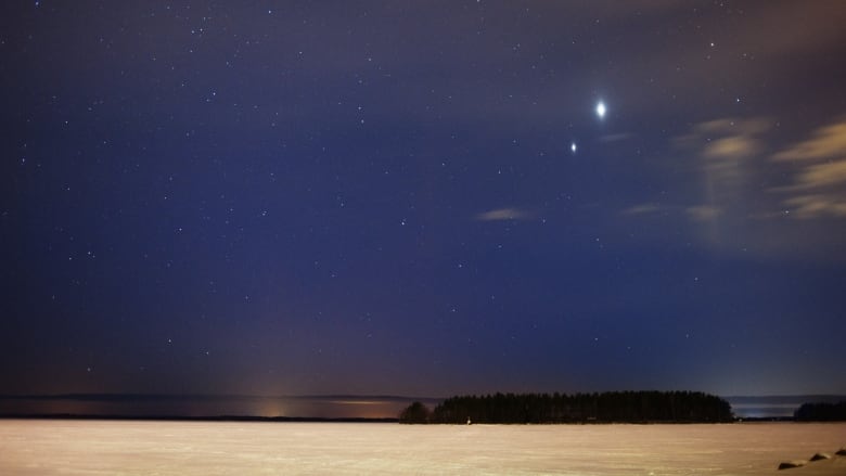 An evening sky over a frozen lake shows two bright star-like objects, which are Jupiter and Venus.