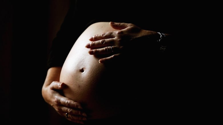 Hands on the belly of an expectant mother.