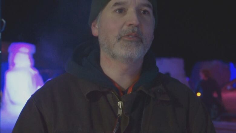 A man looks ahead, standing in front of an ice sculpture.