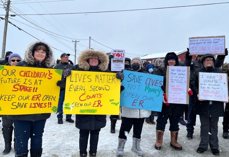 Six people stand next to each other, all holding up posters that have different demands for emergency services in Whitbourne written on them.