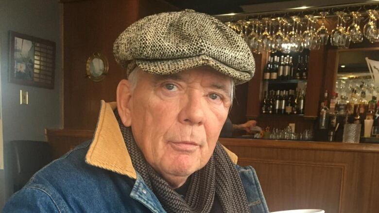 A man sitting in a cafe wears a hat.