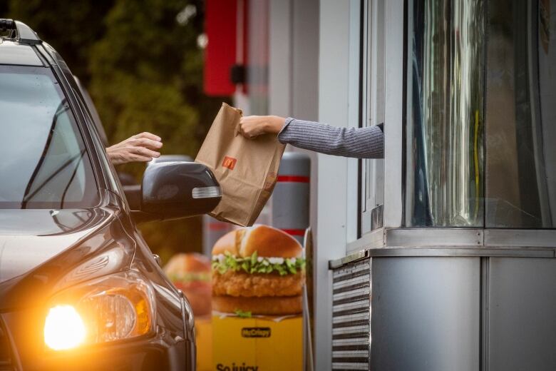 A person in a car picks up food from a drive-thru window.