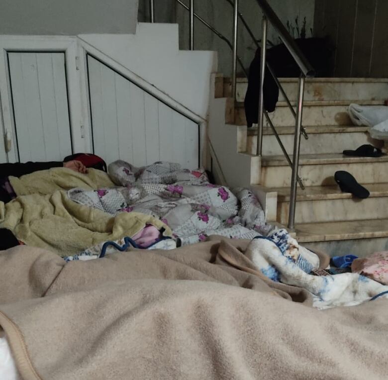 A pile of blankets and sleeping people in the lobby of an apartment building. 