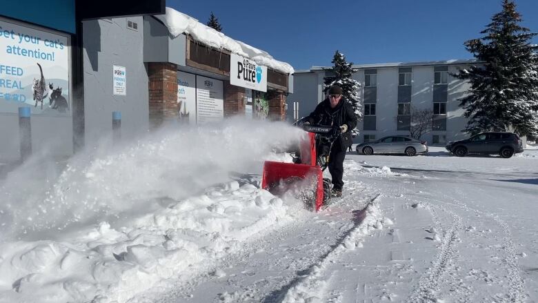 A man snowblows a sidewalk