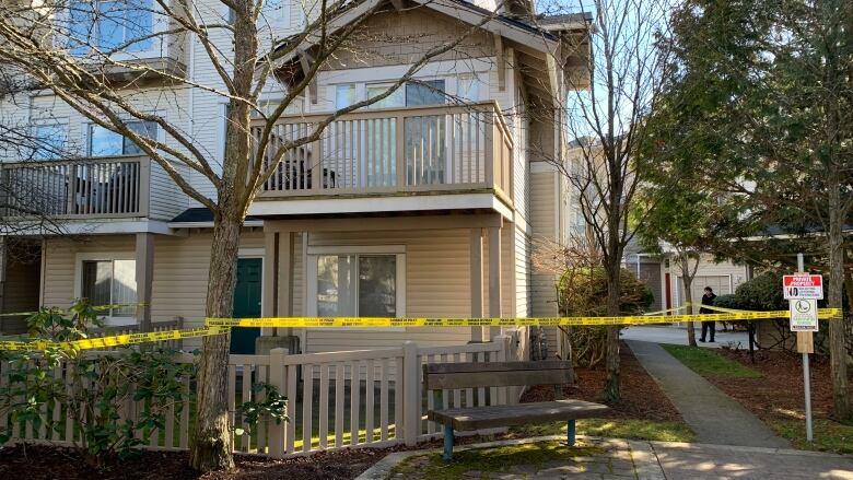 Police tape lines the yard of a townhome