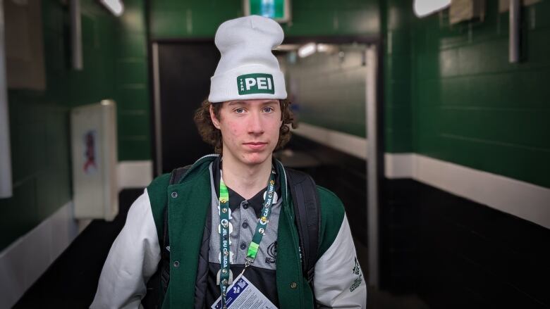 A teenager with a beanie hat with a green logo on the front that says 