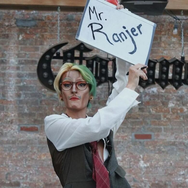 A drag king performer holds up his drag name. 