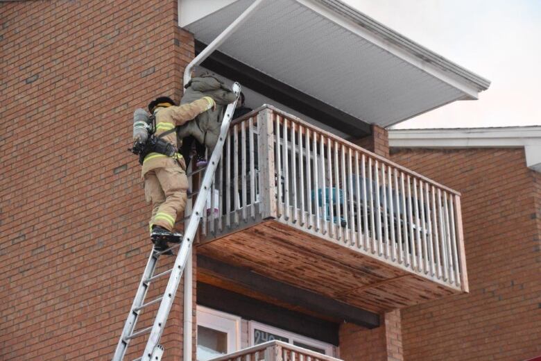 A firefighter helps a child off a balcony onto a ladder.