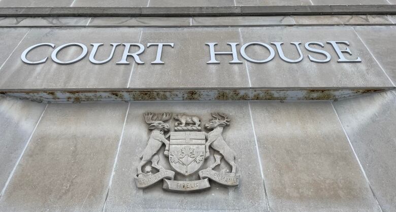 A grey stone block wall with the words 'Court House' and the coat of arms of Ontario.