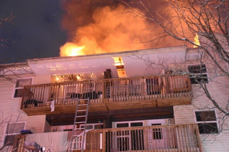 Flames break through the roof of an apartment building.