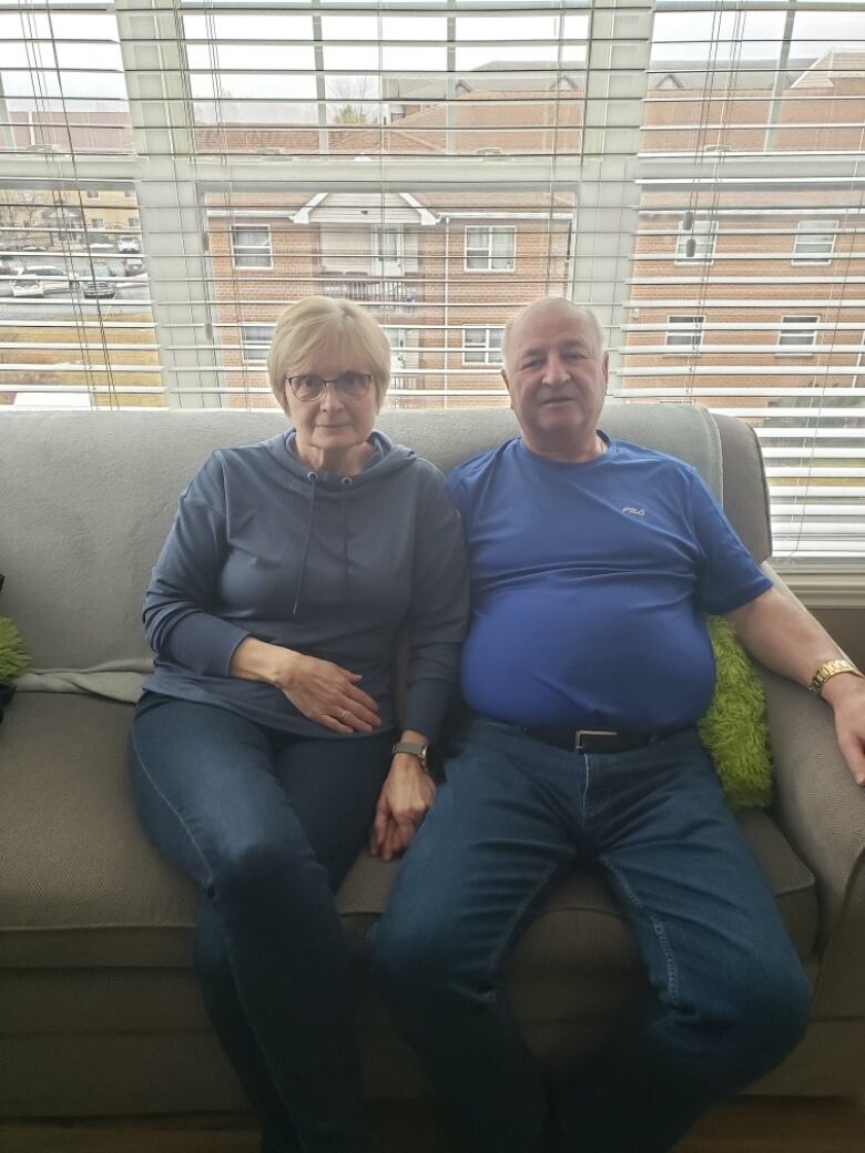 An elderly couple sits on a sofa