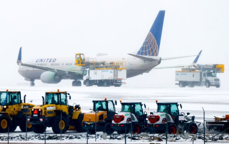 A large plane with small snowplows in the forefront.