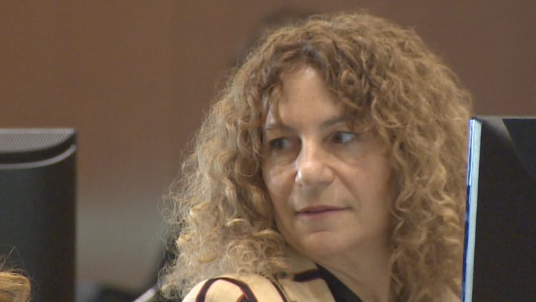 A woman with curly hair sitting in front of a screen