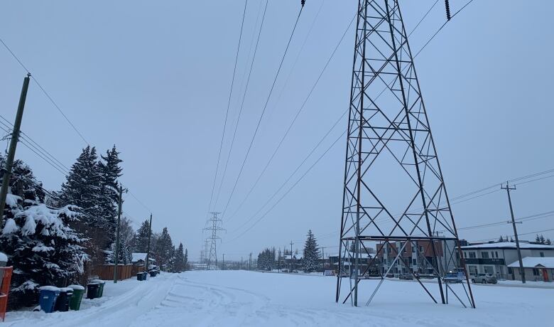 A snowy lot of empty land under powerlines.