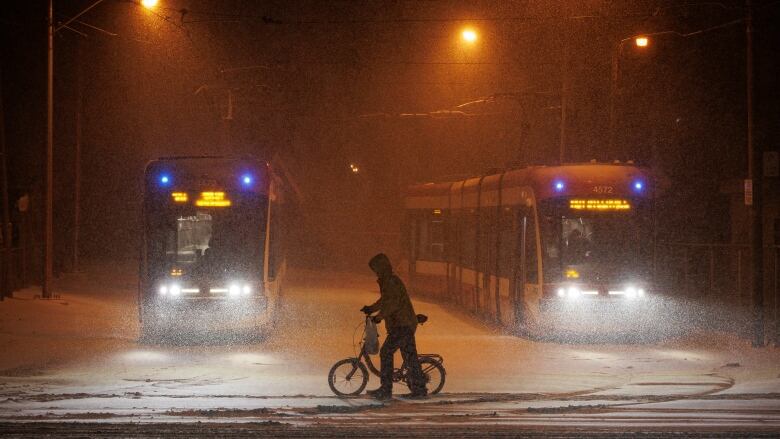 A person walks a bike through blowing snow in Torontos Beaches neighbourhood on Feb. 22, 2023.