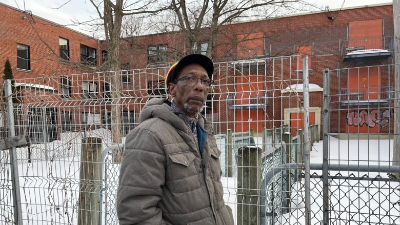 A man standing in front of a fenced off building