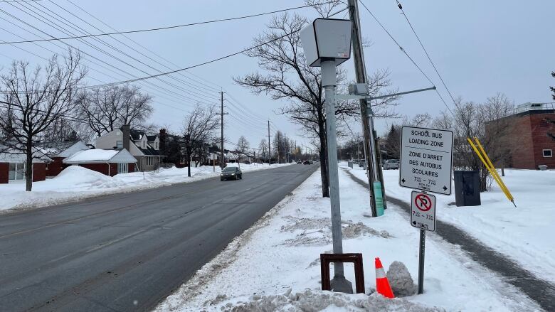 The back of a speed camera along a snowy street.