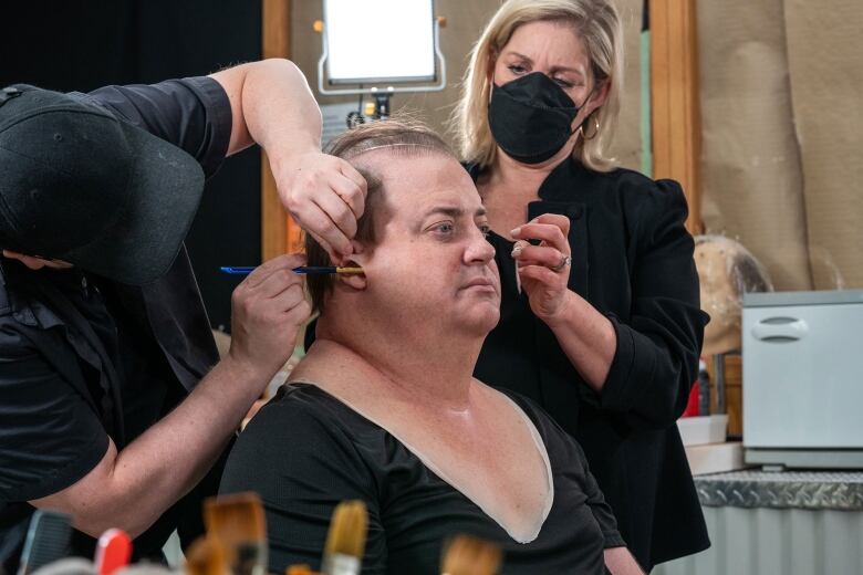 Adrien Morot adds a bit of glue to Brendan Fraser's face while Annemarie Bradley styles his hair.