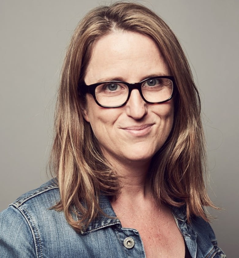 A woman wearing glasses poses for a professional headshot.