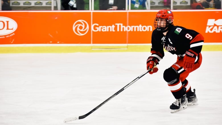 A hockey player wearing a Yukon jersey skates down the ice.