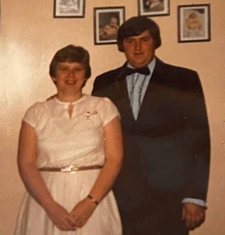 A woman, left, and a man, right, stand next to each other and smile. Both are wearing formal attire.