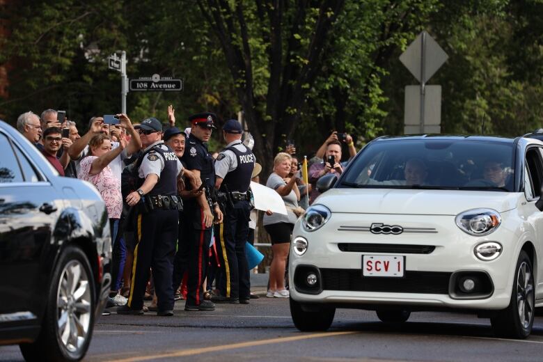 Pope Francis smiles as crowds, held back by police officers, wave to him outside Sacred Heart Catholic Church of the First Peoples in Edmonton.