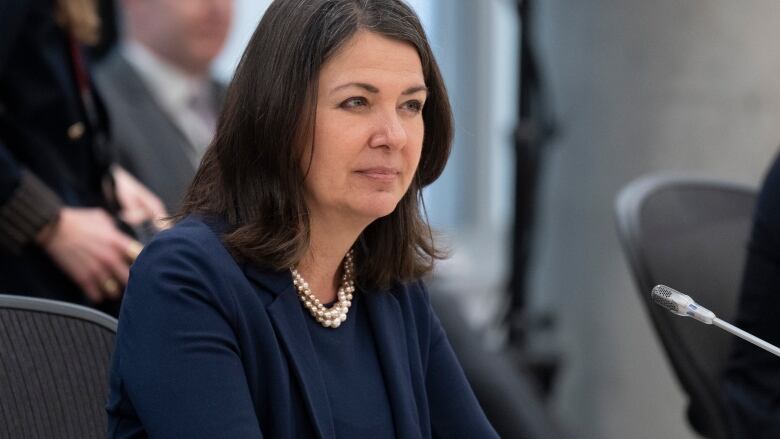 Alberta Premier Danielle Smith sits at a table with a microphone near her, as she waits for a meeting on health care with the prime minister to begin, Tuesday, February 7, 2023, in Ottawa. 