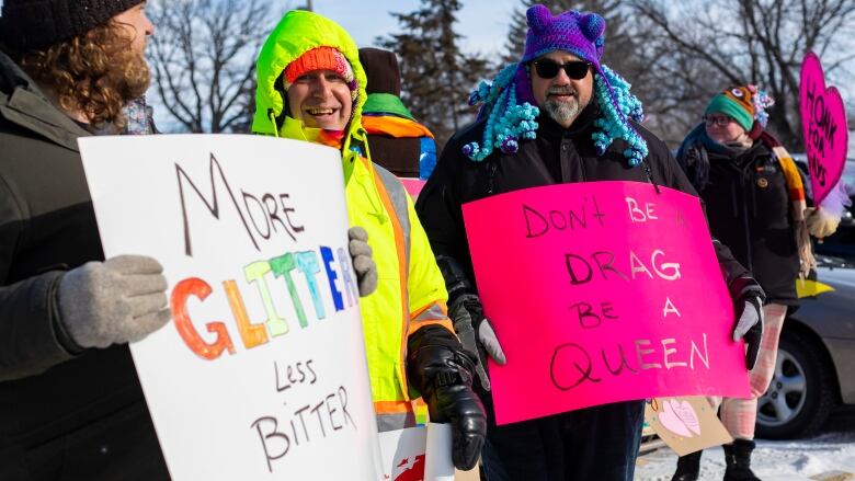 Ralliers dressed in winter gear hold pro LGBTQ signs.