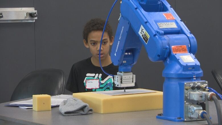 A boy is seen using a 3D printer.